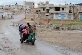 syrie famille fuyant un village en ruine.jpg