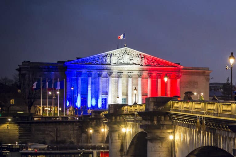 L'Assemblée nationale, de nuit, illuminée aux couleurs du drapeau français.